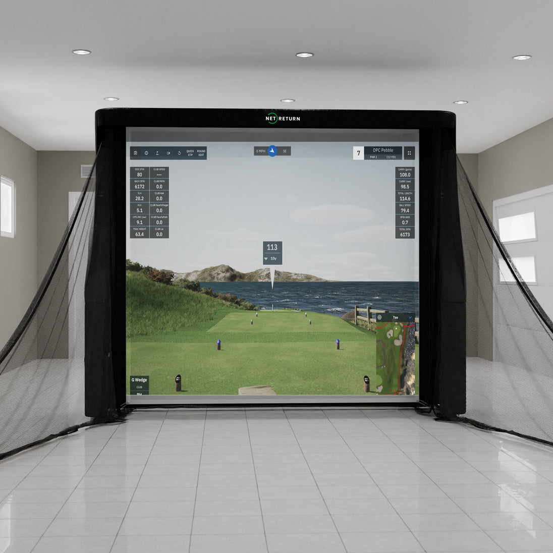 Indoor golf simulator setup with large screen displaying a golf course scene, surrounded by black netting.