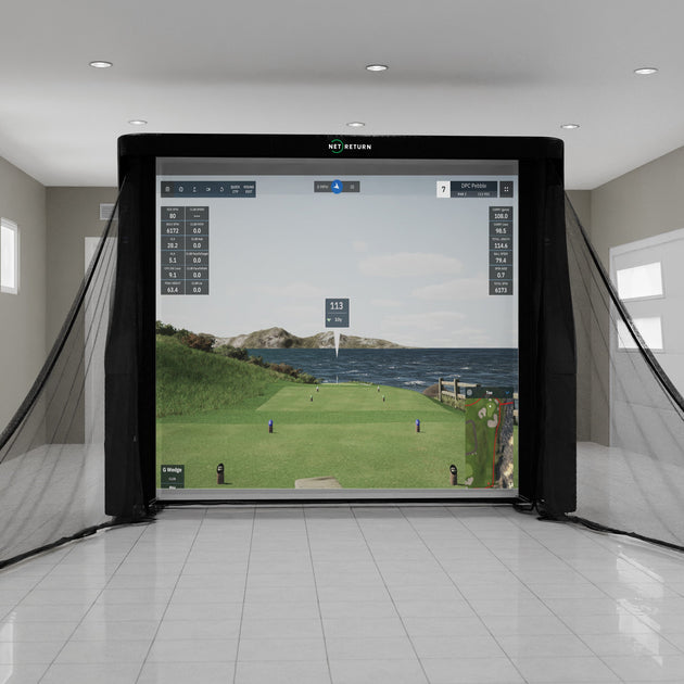 Indoor golf simulator setup with large screen displaying a golf course scene, surrounded by black netting.
